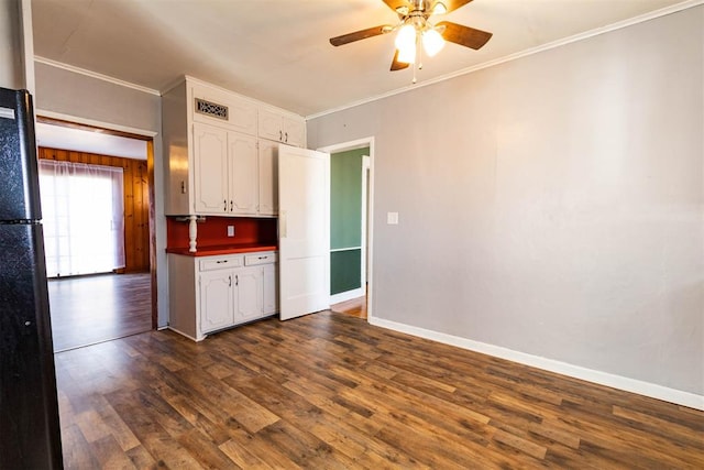 kitchen with white cabinetry, ceiling fan, dark hardwood / wood-style flooring, crown molding, and black refrigerator