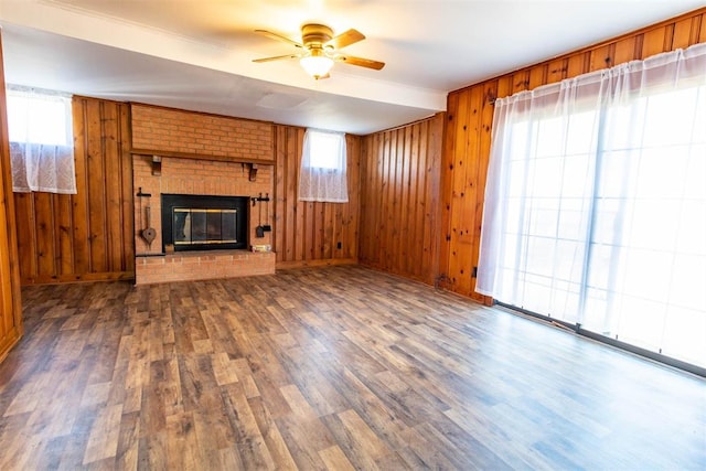 unfurnished living room with wooden walls, a fireplace, ceiling fan, and dark hardwood / wood-style floors