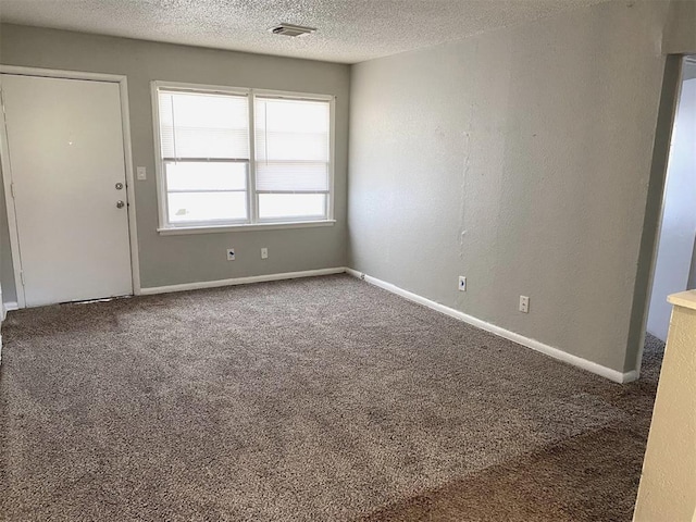 carpeted empty room featuring a textured ceiling