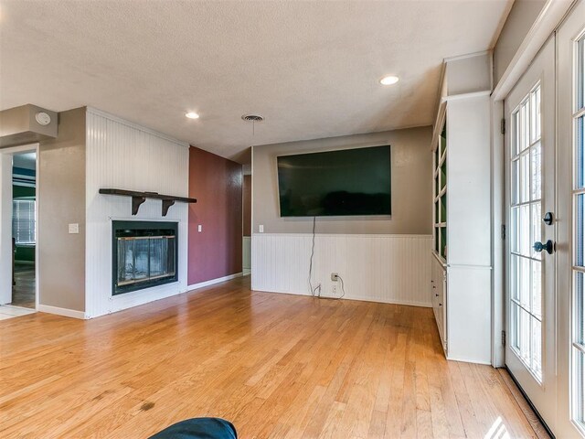 unfurnished living room with a fireplace, light hardwood / wood-style flooring, and a healthy amount of sunlight