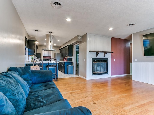 living room featuring a textured ceiling, light hardwood / wood-style floors, and a fireplace