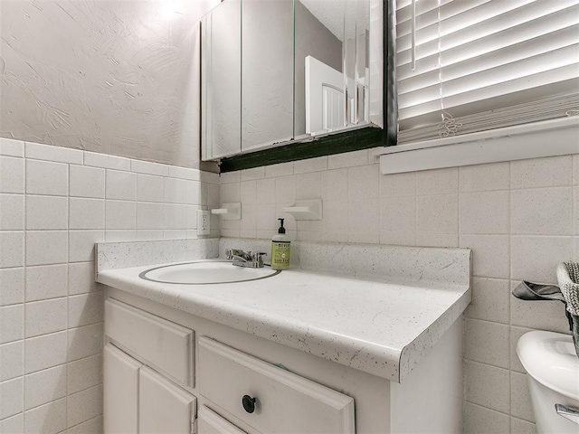 bathroom featuring vanity, toilet, and tile walls