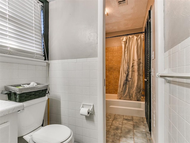 bathroom with tile patterned floors, shower / bath combo, toilet, and tile walls