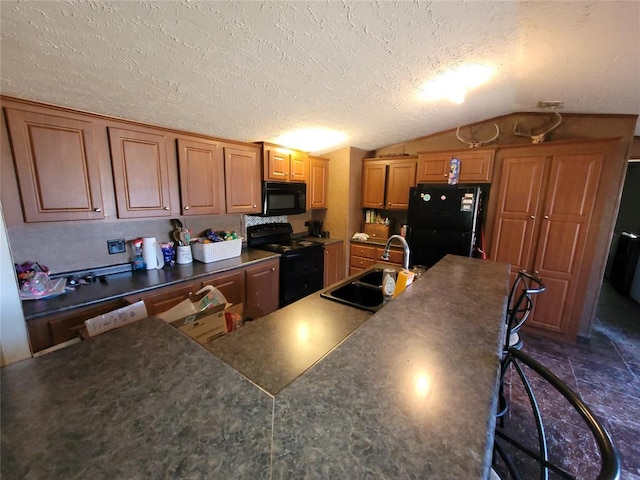 kitchen with a breakfast bar, black appliances, sink, vaulted ceiling, and a textured ceiling