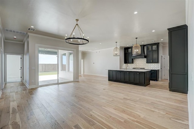 kitchen with a center island, crown molding, light hardwood / wood-style floors, decorative light fixtures, and custom exhaust hood