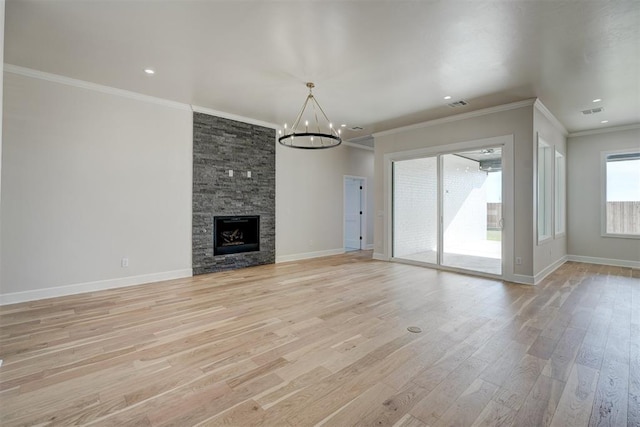 unfurnished living room with crown molding, light wood-type flooring, a fireplace, and a chandelier