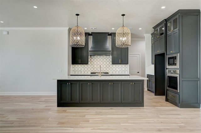 kitchen featuring hanging light fixtures, an inviting chandelier, an island with sink, custom range hood, and appliances with stainless steel finishes