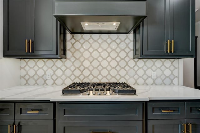 kitchen with decorative backsplash, light stone counters, stainless steel gas cooktop, and range hood