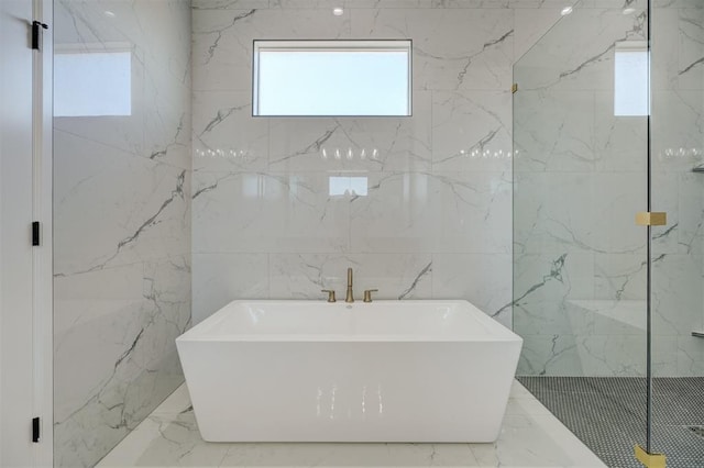 bathroom featuring shower with separate bathtub and tile walls