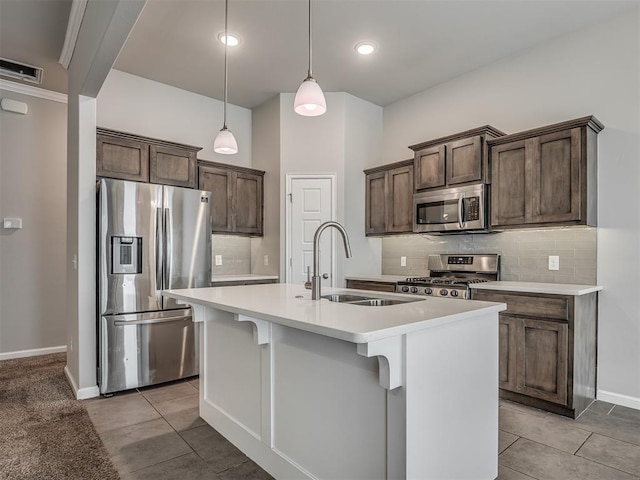 kitchen featuring pendant lighting, stainless steel appliances, a kitchen island with sink, and sink