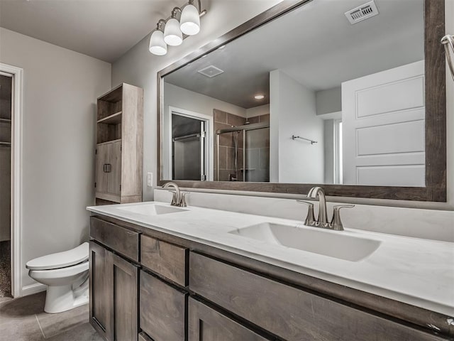 bathroom with tile patterned flooring, vanity, toilet, and a shower with shower door