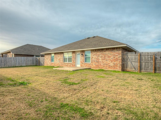 back of house with a lawn and a patio