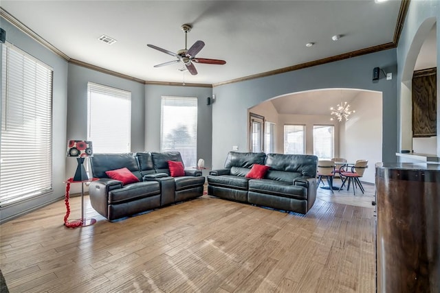 living room with ceiling fan with notable chandelier, light wood-type flooring, a wealth of natural light, and crown molding