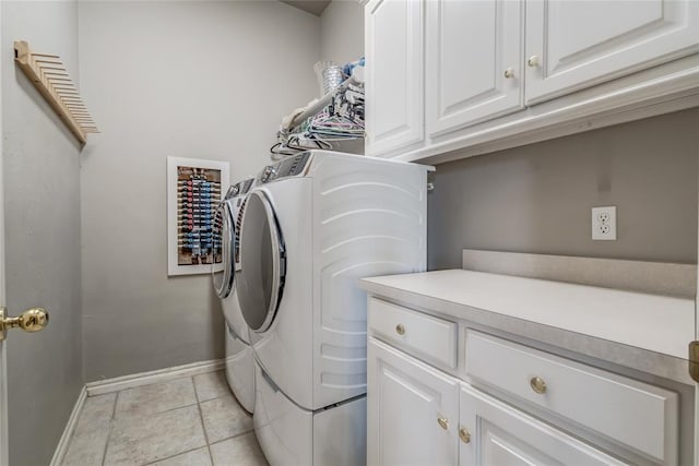 laundry room featuring washing machine and clothes dryer, light tile patterned floors, and cabinets