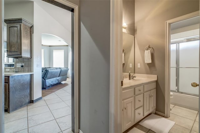 bathroom with tile patterned flooring, a healthy amount of sunlight, shower / bath combination with glass door, and backsplash