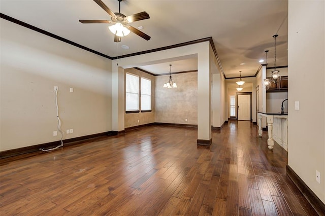 empty room with ceiling fan with notable chandelier, crown molding, and dark wood-type flooring