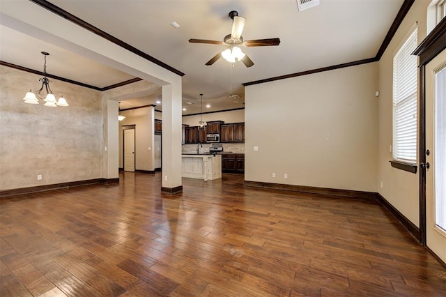 unfurnished living room with ceiling fan with notable chandelier, dark hardwood / wood-style floors, and ornamental molding