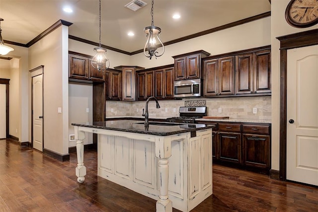 kitchen with pendant lighting, dark hardwood / wood-style flooring, stainless steel appliances, and an island with sink