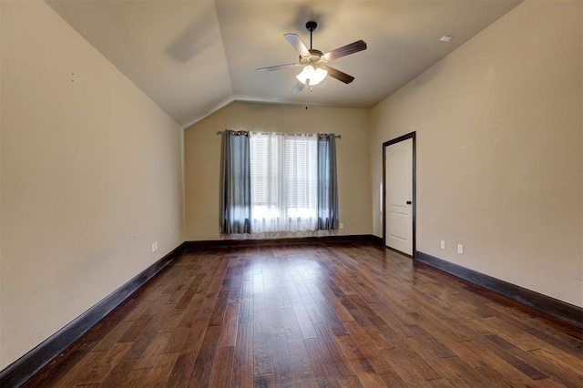 spare room with dark hardwood / wood-style floors, vaulted ceiling, and ceiling fan