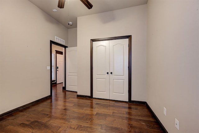 unfurnished bedroom with ceiling fan, dark wood-type flooring, and a closet