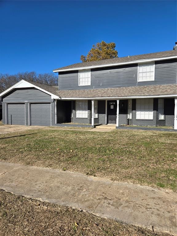 front facade with a front lawn, a porch, and a garage