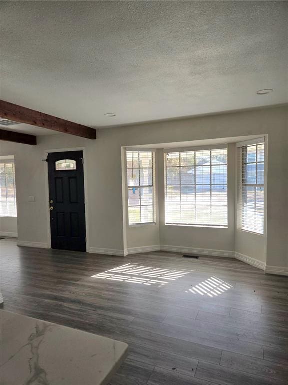 entryway with beamed ceiling, a textured ceiling, and dark wood-type flooring