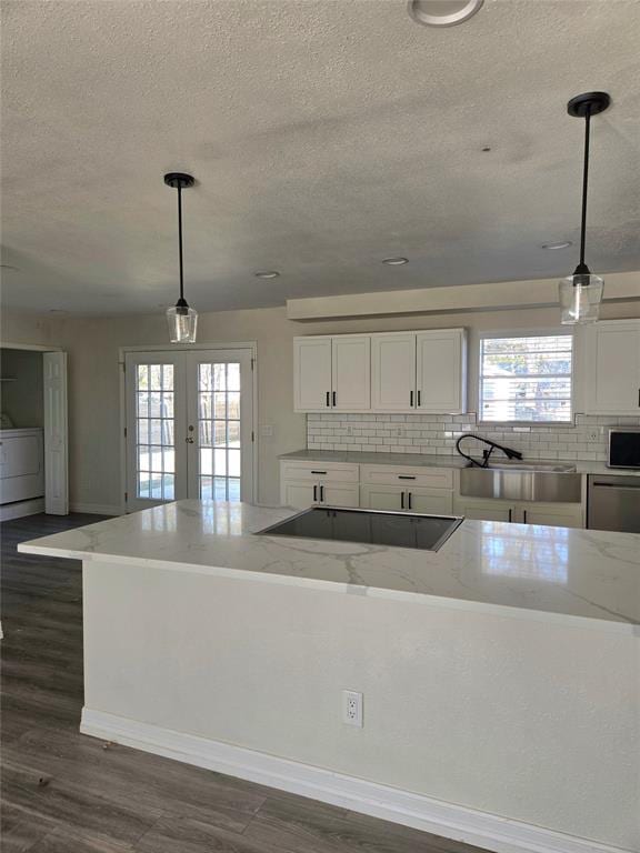 kitchen featuring french doors, dark wood-type flooring, pendant lighting, washer / clothes dryer, and white cabinetry