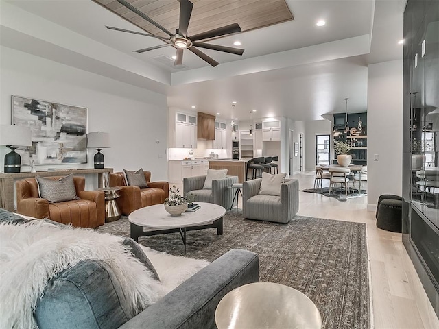 living room featuring ceiling fan, a raised ceiling, wooden ceiling, and light hardwood / wood-style flooring