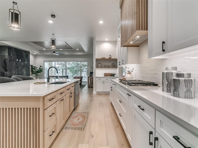 kitchen featuring ceiling fan, sink, stainless steel appliances, hanging light fixtures, and a kitchen island with sink