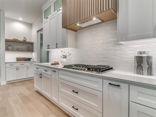 kitchen featuring white cabinets, premium range hood, tasteful backsplash, and light hardwood / wood-style floors