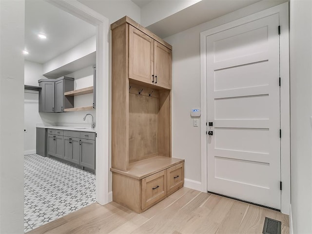 mudroom with light hardwood / wood-style flooring and sink