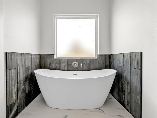 bathroom with a tub to relax in and tile walls