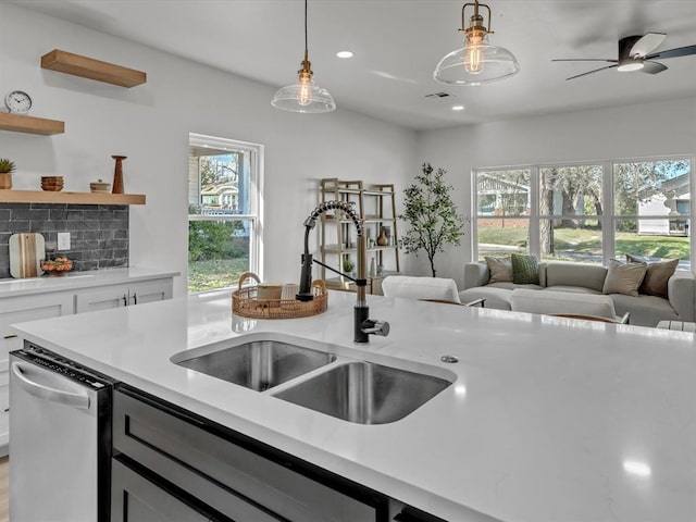 kitchen featuring pendant lighting, sink, dishwasher, white cabinetry, and tasteful backsplash