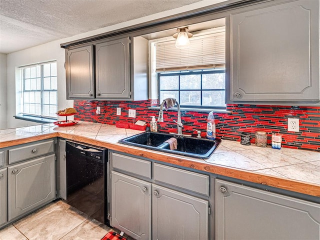 kitchen with tile countertops, dishwasher, gray cabinets, and sink