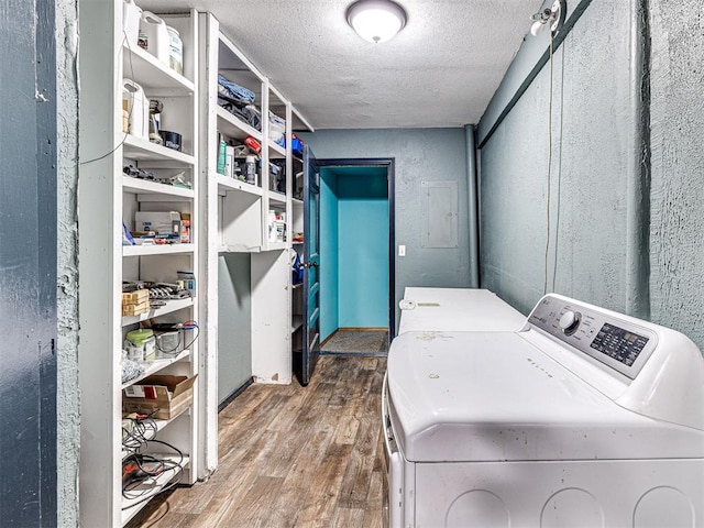 laundry area with electric panel, wood-type flooring, a textured ceiling, and independent washer and dryer