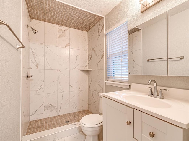 bathroom with a tile shower, vanity, and toilet