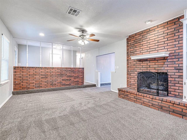 unfurnished living room with ceiling fan, carpet floors, a textured ceiling, and a brick fireplace