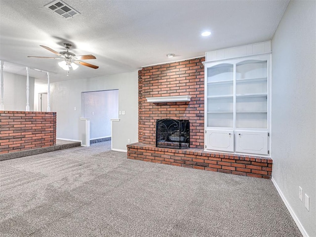 unfurnished living room with carpet flooring, ceiling fan, a textured ceiling, and a brick fireplace