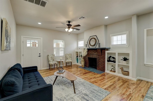 living room with ceiling fan, light hardwood / wood-style floors, and a fireplace