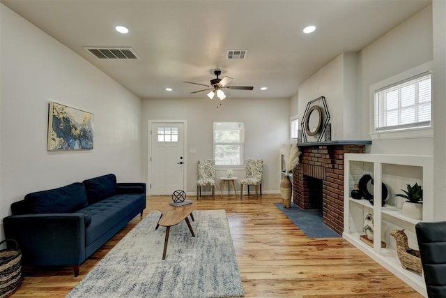 living room featuring ceiling fan, a fireplace, and hardwood / wood-style flooring