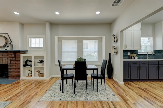 dining area with a fireplace, light hardwood / wood-style floors, and sink