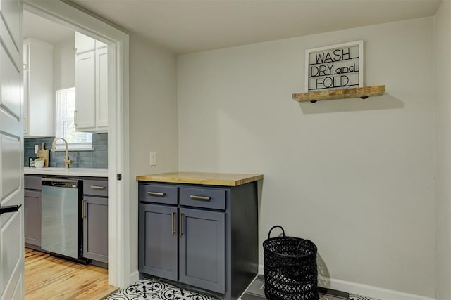 kitchen featuring dishwasher, sink, gray cabinets, light wood-type flooring, and tasteful backsplash