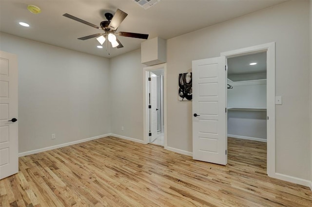 unfurnished bedroom featuring ceiling fan, a closet, light hardwood / wood-style floors, and a spacious closet