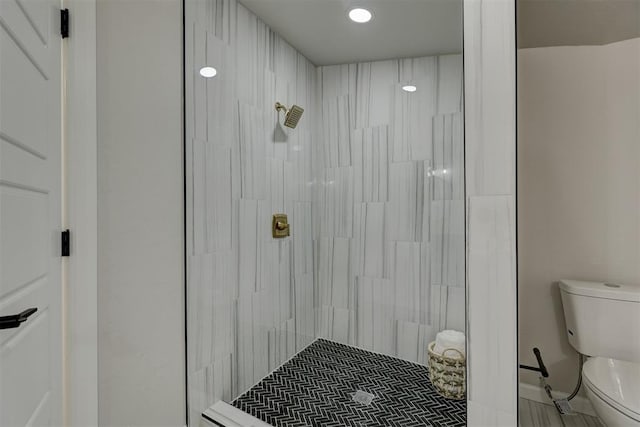 bathroom featuring tiled shower and toilet