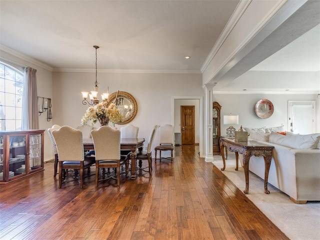 dining space featuring dark hardwood / wood-style floors, ornate columns, ornamental molding, and an inviting chandelier