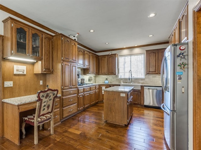 kitchen featuring sink, dark wood-type flooring, stainless steel appliances, a kitchen island, and ornamental molding