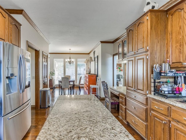 kitchen with dark wood-type flooring, an inviting chandelier, hanging light fixtures, stainless steel fridge, and light stone countertops