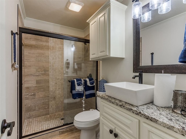 bathroom with hardwood / wood-style floors, vanity, a shower with door, crown molding, and toilet