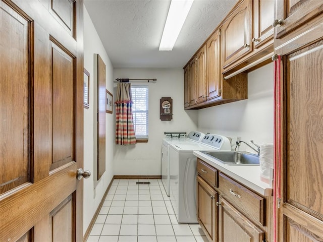 clothes washing area with washer and clothes dryer, light tile patterned floors, cabinets, and sink