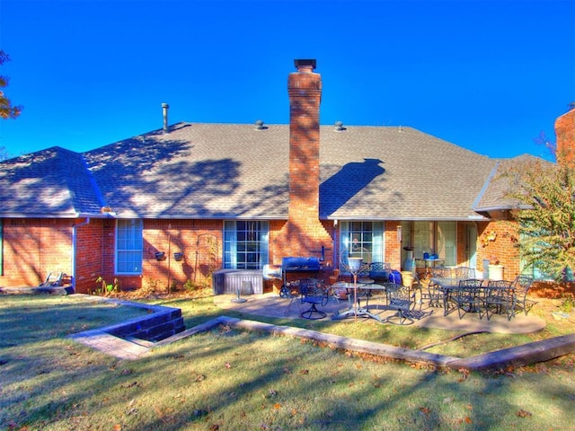 rear view of house featuring a lawn and a patio